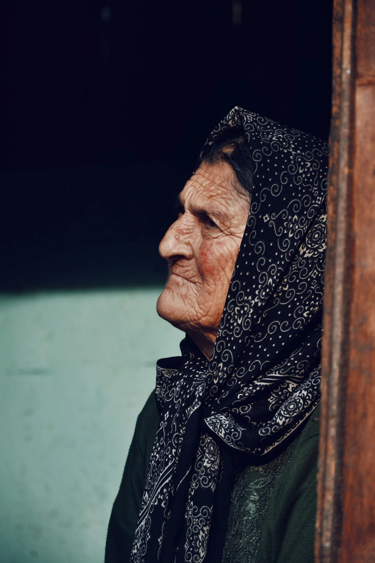 An older woman looks out of a window.