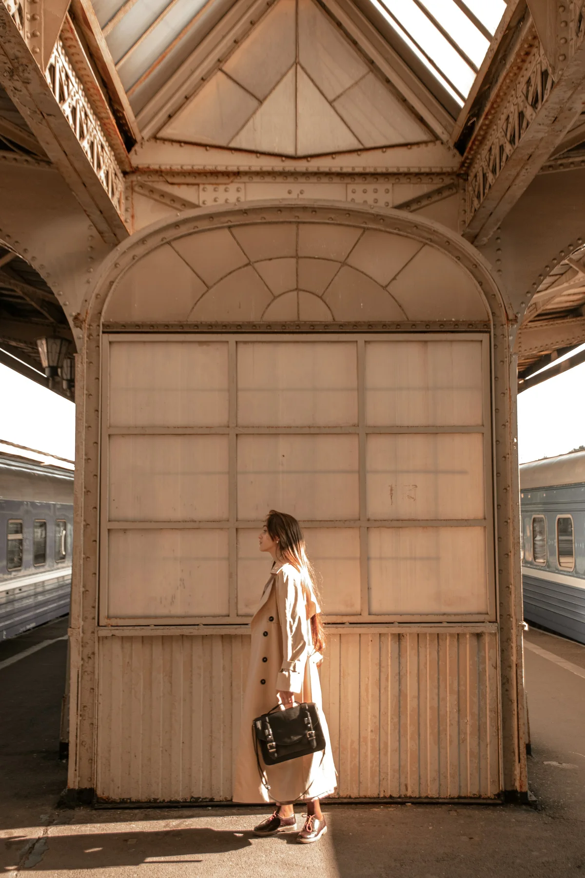 A young woman pauses between trains with her bag.